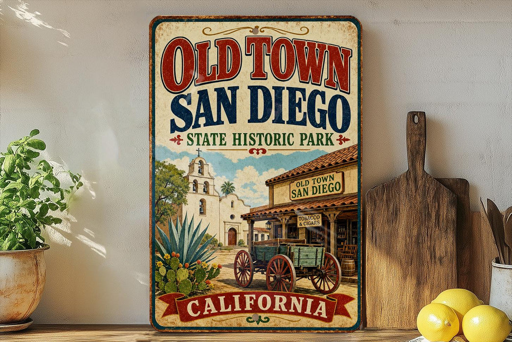 A vintage-style metal sign for Old Town San Diego, California, featuring an illustration of a historic building and a wagon, with a wooden paddle and a potted plant in the foreground.