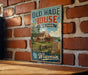 A vintage-style metal sign for Old Wade House State Park in Wisconsin, featuring an illustration of a historic house surrounded by a scenic landscape.