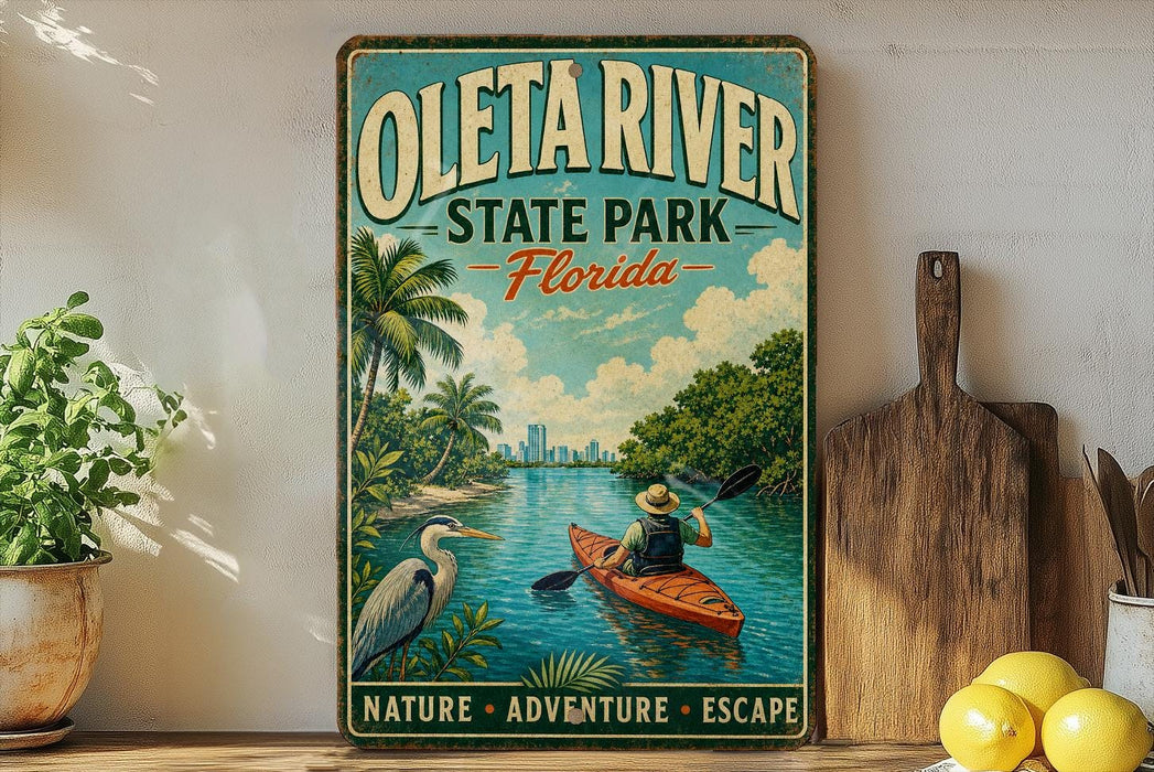 A vintage-style metal sign for Oleta River State Park, Florida, featuring a person kayaking in a river surrounded by palm trees and a city skyline.