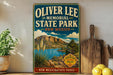 A vintage-style sign for Oliver Lee Memorial State Park in New Mexico, featuring a scenic landscape with mountains, a lake, and desert vegetation.