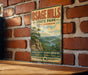 A vintage-style metal sign for Osage Hills State Park in Oklahoma, featuring a scenic landscape with mountains, trees, and a river.
