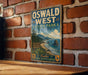 A vintage-style metal sign for Oswald West State Park in Oregon, featuring a scenic coastal landscape with mountains, trees, and a beach.