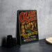 A vintage-style metal sign advertising Ozark Caves, featuring an illustration of the caves and a river, is displayed on a gray concrete surface.