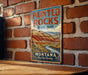 A vintage-style metal sign for Painted Rocks State Park in Montana, featuring a scenic mountain landscape.