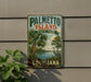 A vintage-style metal sign for Palmetto Island State Park in Louisiana, featuring a palm tree and a bird, mounted on a wall.