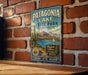 A vintage-style metal sign for Patagonia Lake State Park in Arizona, featuring a desert landscape with a cactus, a lake, and mountains.