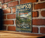 A vintage-style metal sign for Patapsco Valley State Park in Maryland, featuring a scenic landscape with a bridge and flowing water.