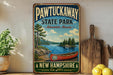 A vintage-style sign for Pawtuckaway State Park, featuring a canoe and a scenic landscape, is displayed on a shelf next to a wooden cutting board and some lemons.