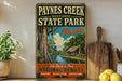 A vintage-style metal sign for Paynes Creek Historic State Park in Florida, featuring a scenic illustration of a river, trees, and a cabin.