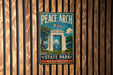 A vintage metal sign for Peace Arch State Park in Washington, featuring an illustration of the arch and surrounding landscape.