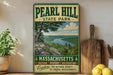 A vintage-style sign for Pearl Hill State Park in Massachusetts, featuring a scenic landscape with a river and trees.