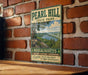 A vintage-style metal sign for Pearl Hill State Park in Massachusetts, featuring a scenic landscape with a lake and mountains.