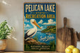 A vintage-style metal sign for Pelican Lake State Recreation Area in South Dakota, featuring a large white pelican and a scenic landscape.