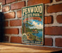 A vintage-style metal sign for Penwood State Park in Connecticut, featuring a scenic illustration of a forest and a lake.
