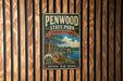 A vintage metal sign for Penwood State Park in Connecticut, featuring a scenic landscape with a lake, trees, and a cabin.
