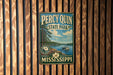A vintage metal sign for Percy Quinn State Park in Mississippi, featuring a scenic image of a lake and a boat.
