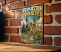 A vintage-style metal sign for Poshastin Pinnacles State Park in Washington, featuring a scenic mountain landscape.