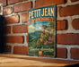 A vintage-style metal sign for Petit Jean State Park in Arkansas, featuring a scenic landscape with a cliff and river.