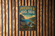 A vintage-style metal sign for Pfeiffer Big Sur State Park, featuring a scenic landscape with mountains, water, and a beach.