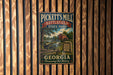 A vintage metal sign for Pickett's Mill Battlefield State Park in Georgia, featuring a scenic illustration of a mill and a river.
