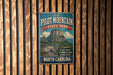 a vintage-style metal sign for Pilot Mountain State Park in North Carolina, mounted on a wooden wall.