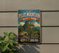 a vintage-style metal sign for Pilot Mountain State Park in North Carolina, with a mountain landscape and scenic trails visible.
