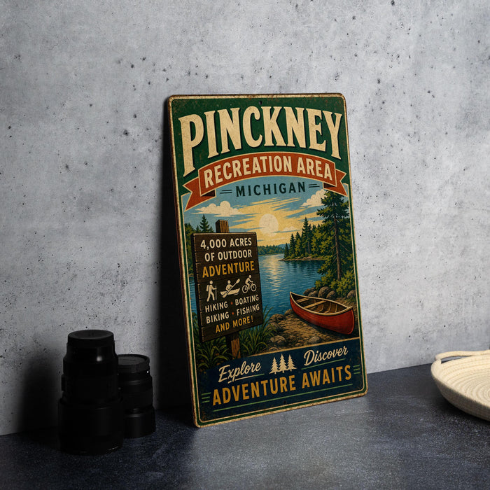 A vintage metal sign advertising the Pinckney Recreation Area in Michigan, featuring a scenic image of a lake and forest.