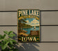 A vintage-style metal sign for Pine Lake State Park in Iowa, featuring a scenic image of the lake and surrounding nature.