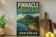 A vintage-style sign for Pinnacle Mountain State Park in Arkansas, featuring a scenic mountain landscape with a lake and pine trees.