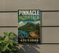 A vintage-style sign for Pinnacle Mountain State Park in Arkansas, featuring a mountain landscape and a lake, mounted on a wall.