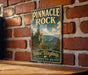 A vintage-style metal sign for Pinnacle Rock State Park in West Virginia, featuring a scenic mountain landscape.