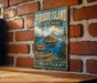 A vintage-style metal sign for Pirogue Island State Park in Montana, featuring a scenic illustration of the island and its surrounding landscape.