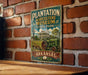 A vintage-style metal sign for the Plantation Agriculture Museum in Arkansas, featuring an illustration of a farm scene with a tractor and a building.