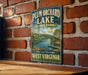 A vintage-style sign for Plum Orchard Lake State Park in West Virginia, featuring a scenic image of the lake surrounded by trees and mountains.