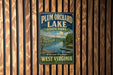 A vintage-style metal sign for Plum Orchard Lake State Park in West Virginia, featuring a scenic image of the lake and surrounding landscape.