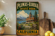 A vintage-style metal sign for Plumas-Eureka State Park in California, featuring a scenic illustration of a historic building and mountains in the background.