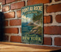 A vintage-style sign for Pointau-Roche State Park, featuring a scenic image of a rocky coastline and a lake, mounted on a brick wall.