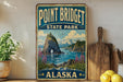 A vintage-style sign for Point Bridget State Park in Alaska, featuring a scenic landscape with mountains, water, and a rocky island.