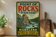 A vintage-style metal sign for Point of Rocks State Park in Maryland, featuring a scenic mountain landscape with a river and lush greenery.