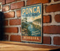 A vintage-style sign for Pona State Park in Nebraska, featuring a scenic landscape with a river and cliffs.