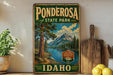 A vintage-style sign for Ponderosa State Park in Idaho, featuring a scenic landscape with a lake, mountains, and pine trees.