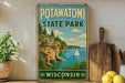 A vintage-style sign for Potawatomi State Park in Wisconsin, featuring a scenic image of a lake with a sailboat and cliffs.