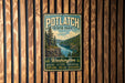 A vintage-style metal sign for Potlatch State Park, featuring a scenic landscape with a river and pine trees, mounted on a wooden wall.