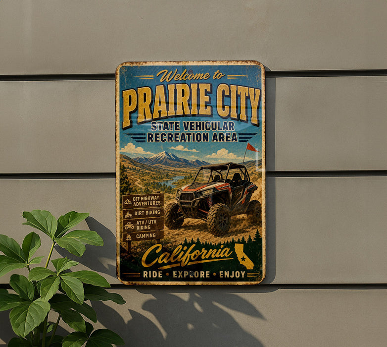 a vintage-style metal sign that reads "Welcome to Prairie City" and "State Vehicular Recreation Area", with an illustration of an off-road vehicle in the background.