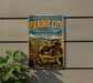 a vintage-style metal sign that reads "Welcome to Prairie City" and "State Vehicular Recreation Area", with an illustration of an off-road vehicle in the background.