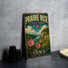 A vintage-style sign for Prairie Rose State Park, featuring a scenic landscape with a river, mountains, and flowers.
