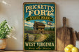 A vintage-style sign for Prickett's Fort State Park in West Virginia, featuring a wooden cabin and a sign that reads "Welcome to the Frontier Heritage".