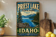 A vintage-style sign for Priest Lake State Park in Idaho, featuring a scenic mountain landscape with a lake and pine trees.