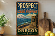 a vintage-style sign for the Prospect State Scenic Viewpoint in Oregon, with a mountain landscape and a stone structure in the foreground.