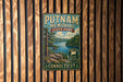 A vintage metal sign for Putnam Memorial State Park in Connecticut, featuring a scenic landscape with a lake and mountains.